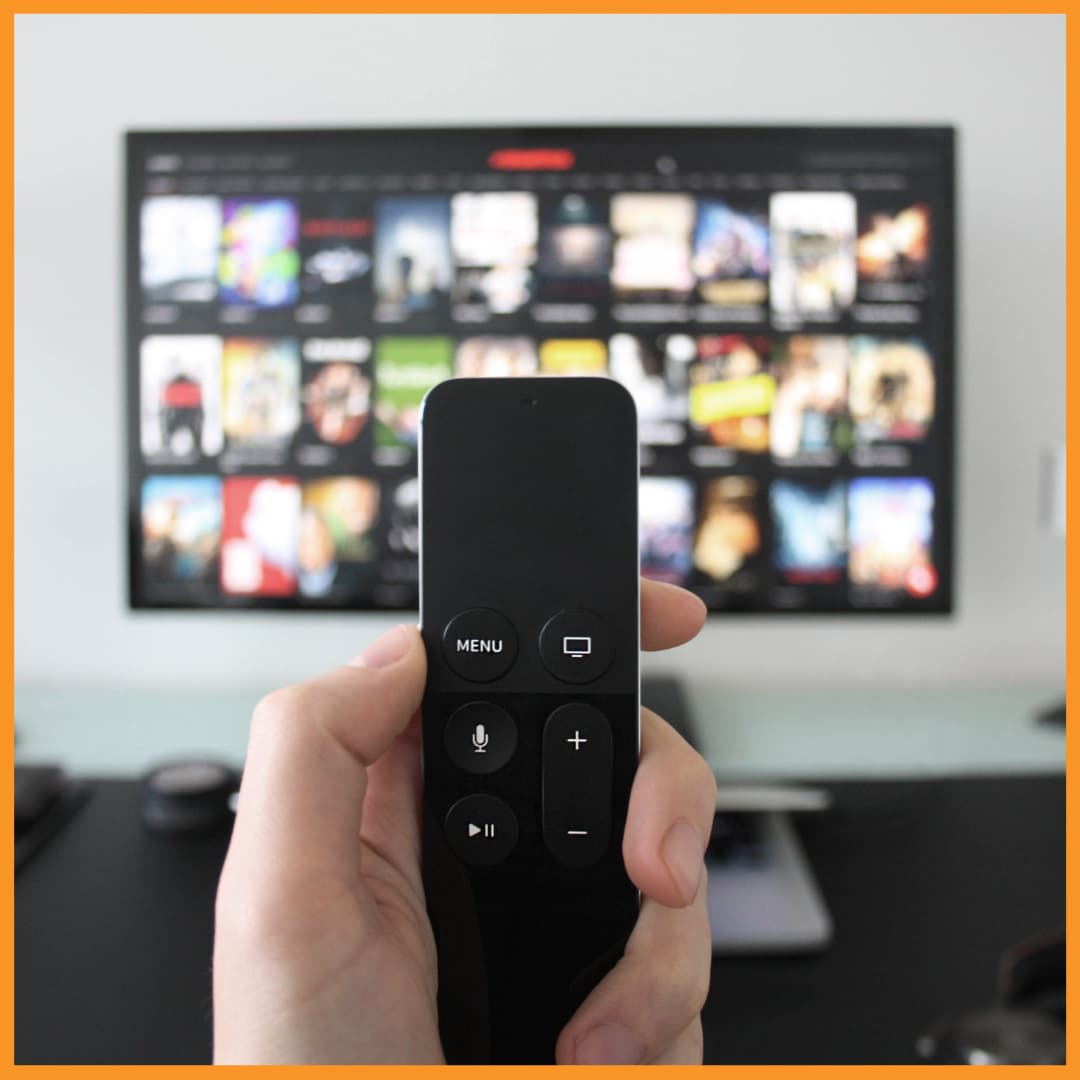 Hand holding TV remote with streaming content