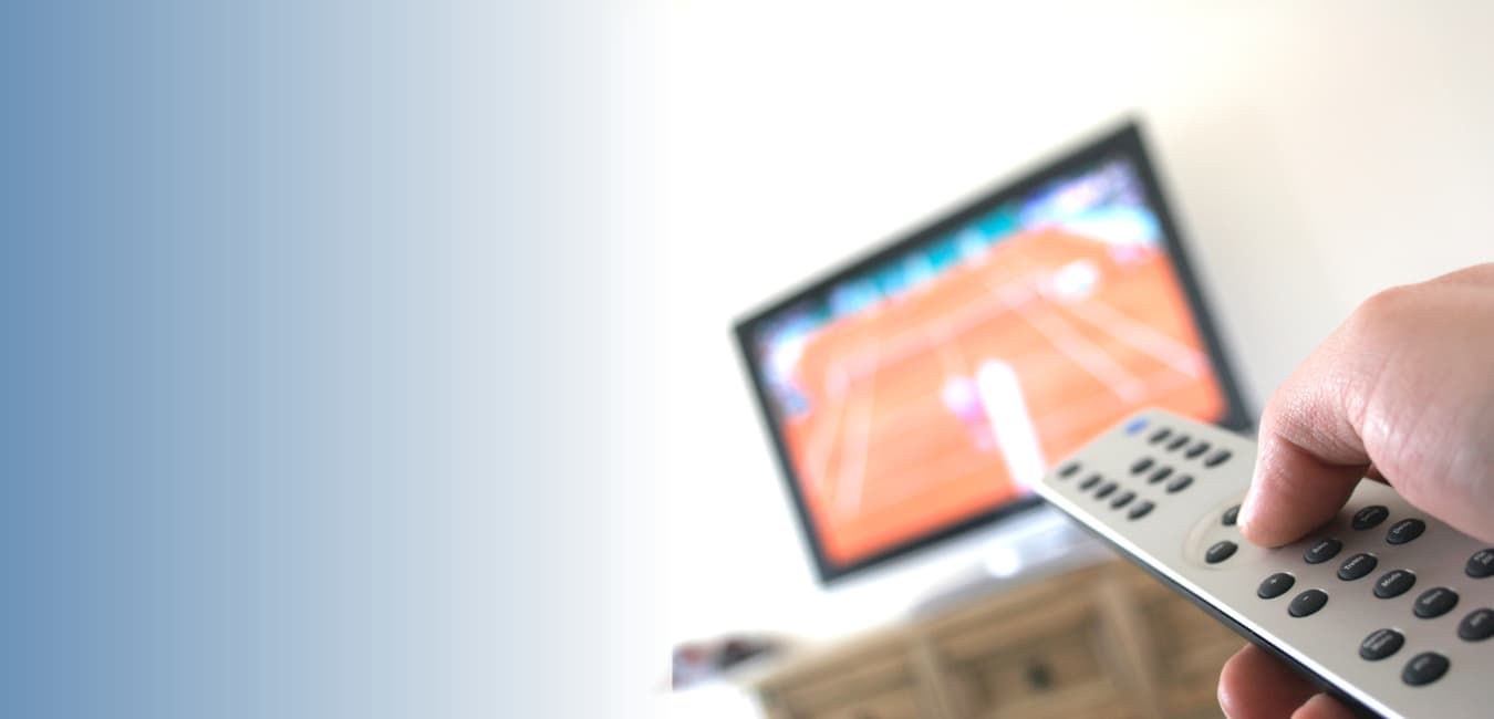 Hand holding TV remote pointed at screen