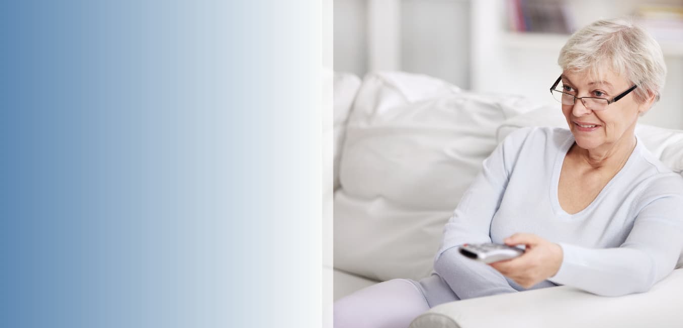 Senior woman smiling while watching television